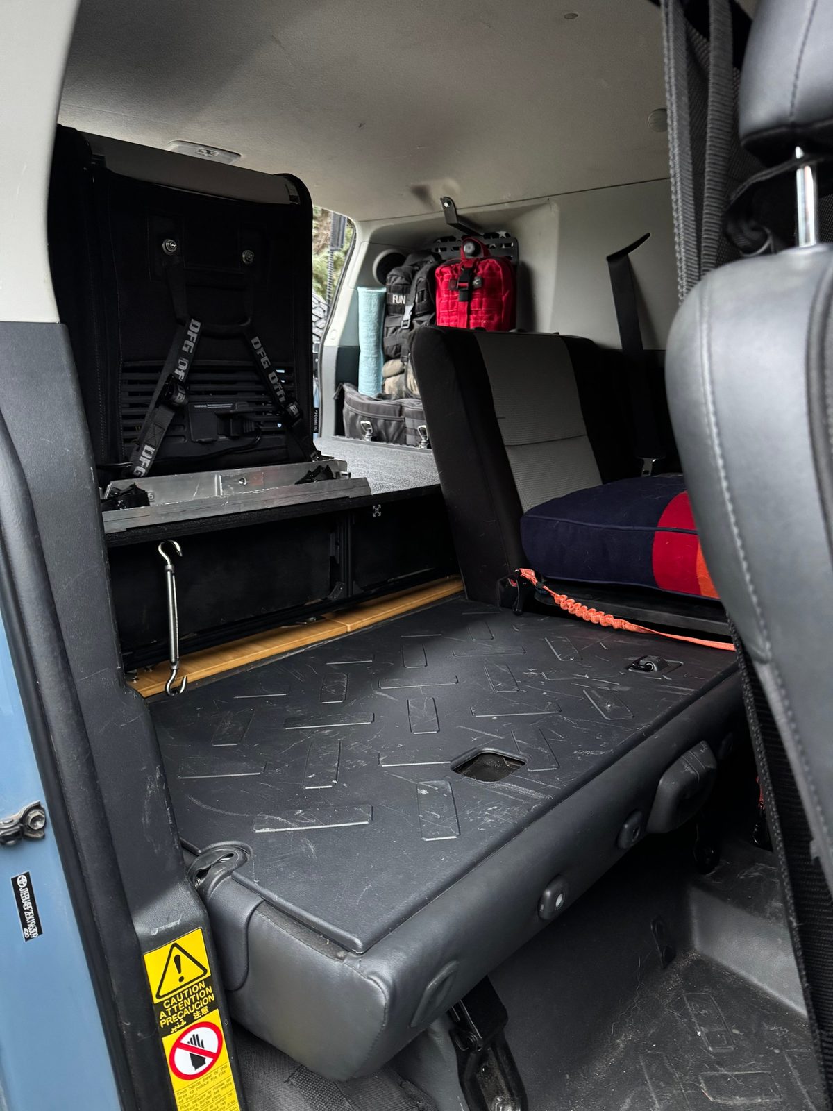 Rear tie-down: the turnbuckle hooked to the top rear rail of the frame, running down to the floor tie-down point beside the seat