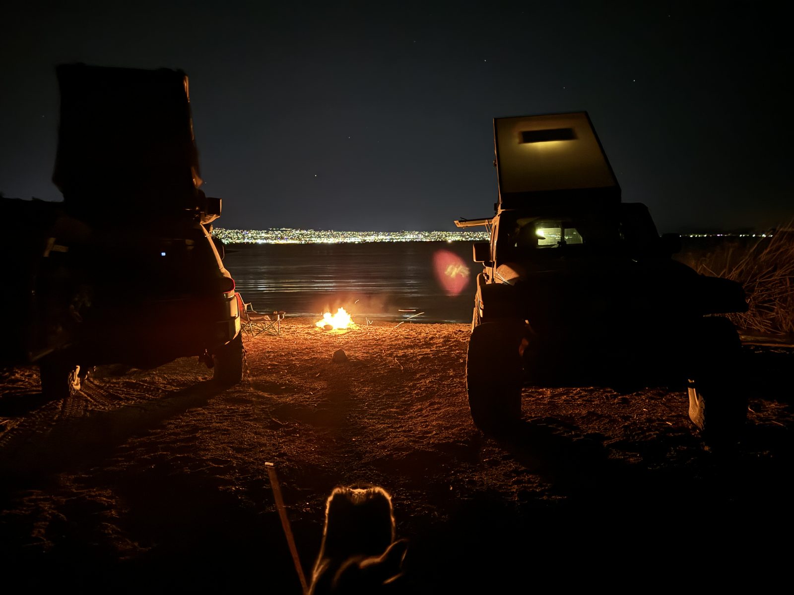 Both rigs by a campfire on the beach at night