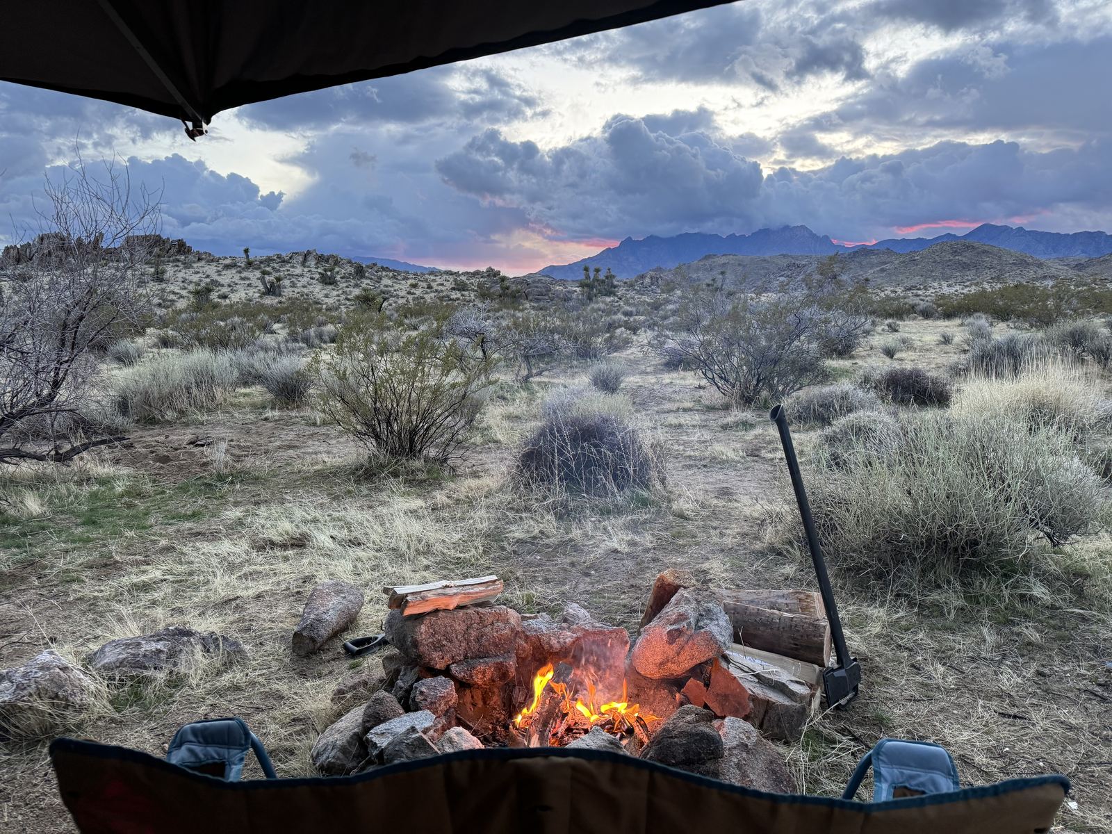 A campfire with mountains and storm clouds behind