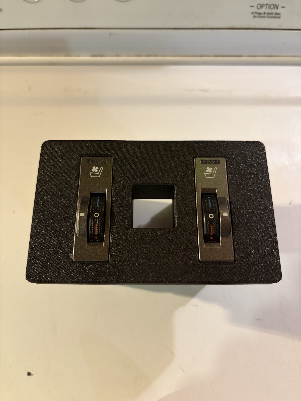 The printed bezel on the bench with both switches clipped in and the USB-C slot between them